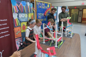Three students demo their homemade roller coasters