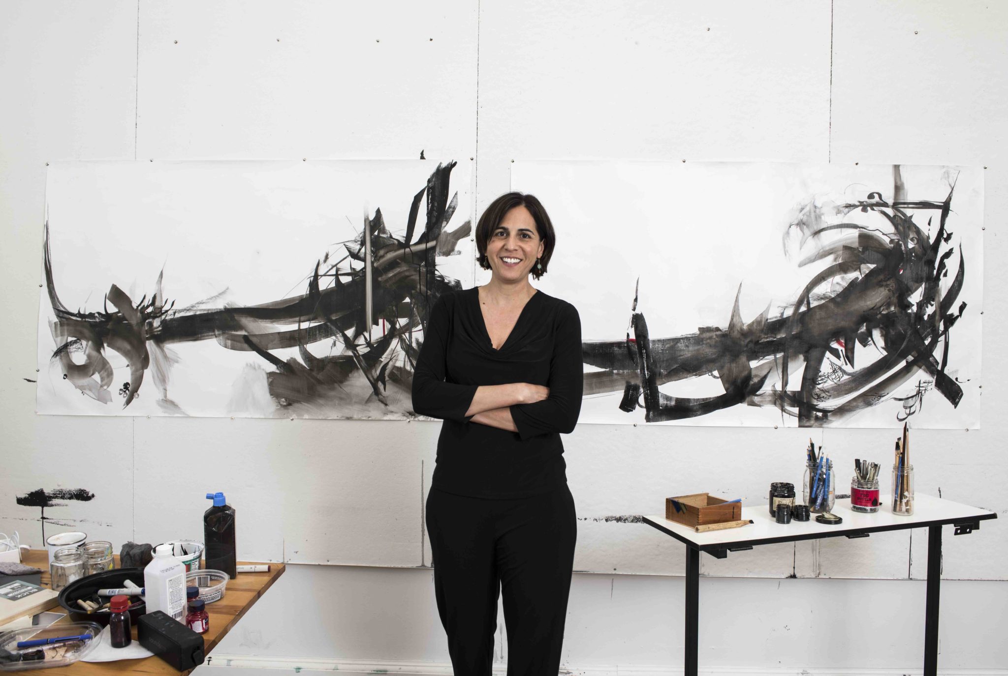 Dr. Moghbeli standing in front of her art.