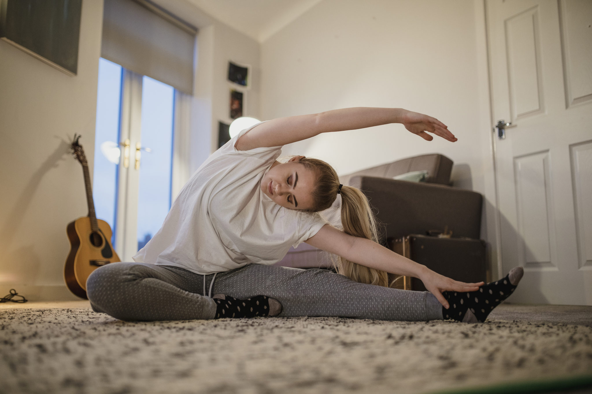 University student is doing yoga in her living room.