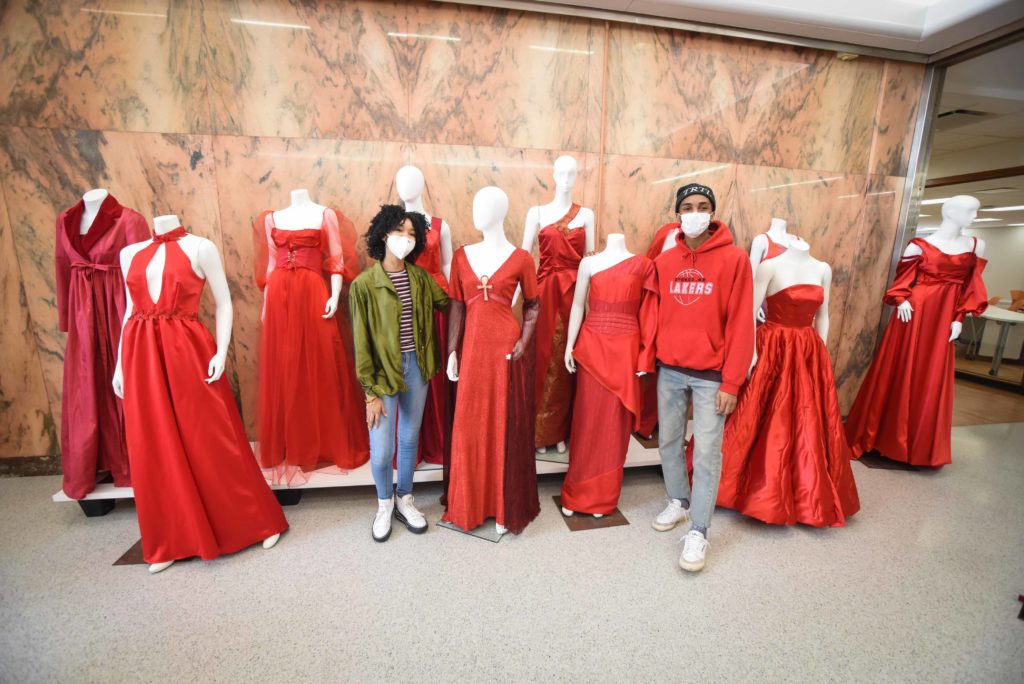 fashion students stand next to their red dresses